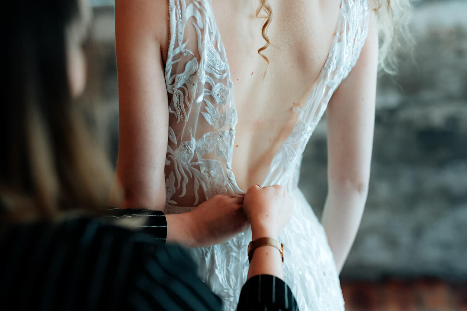 Hochzeitsplanerin hilft Braut ihr Kleid anzuziehen